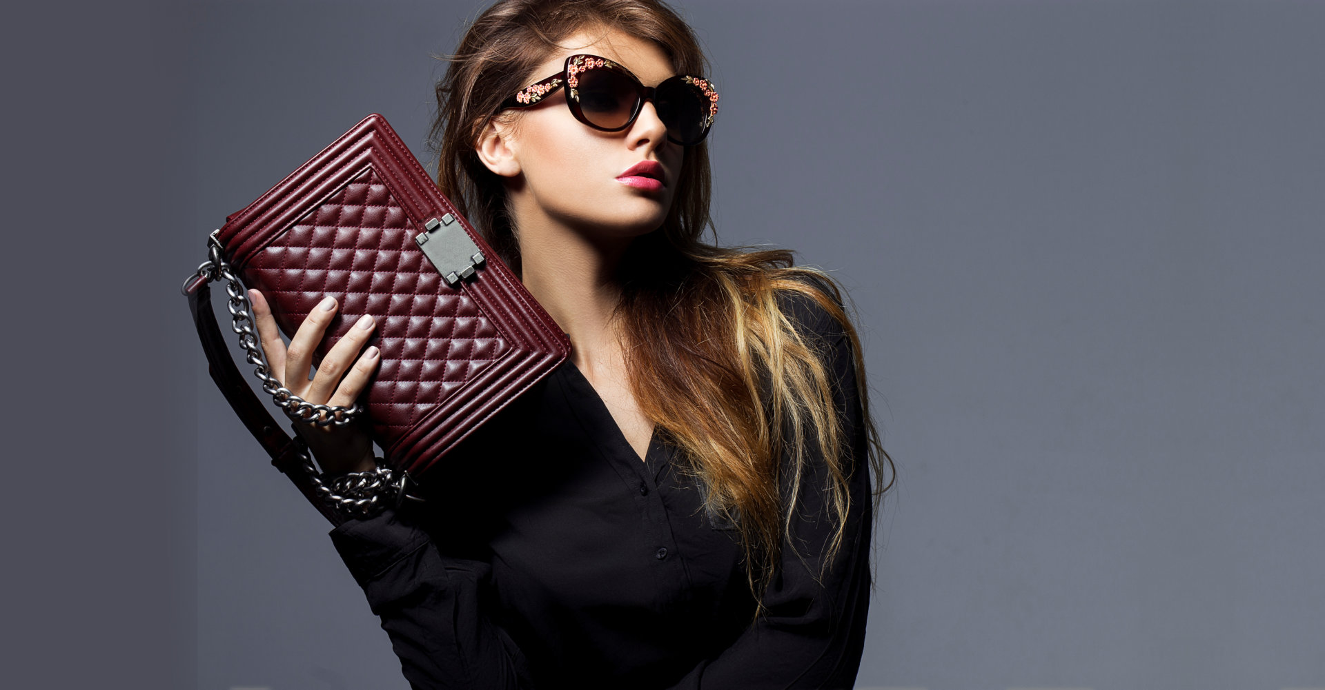 woman holding a bloodred bag on gray background